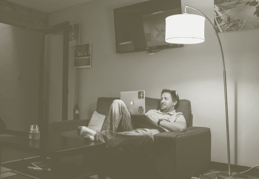 Man on relaxing using a laptop on a living room couch.
