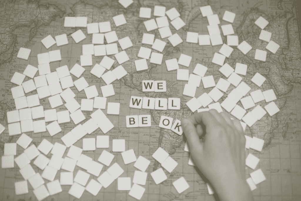 Scrabble blocks on a map spelling out "WE WILL BE OK"