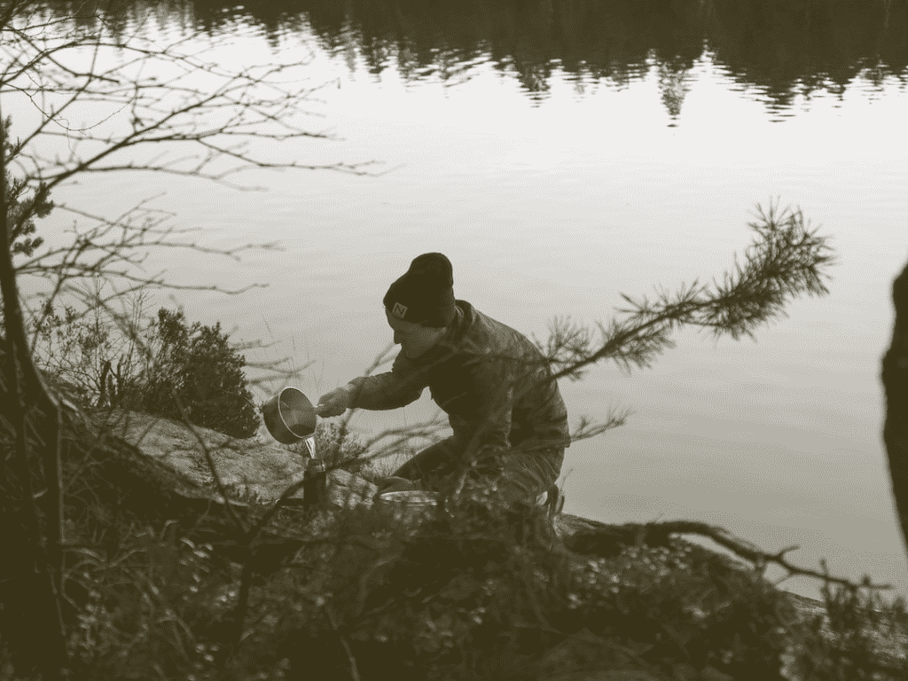 Person collecting water from by lake