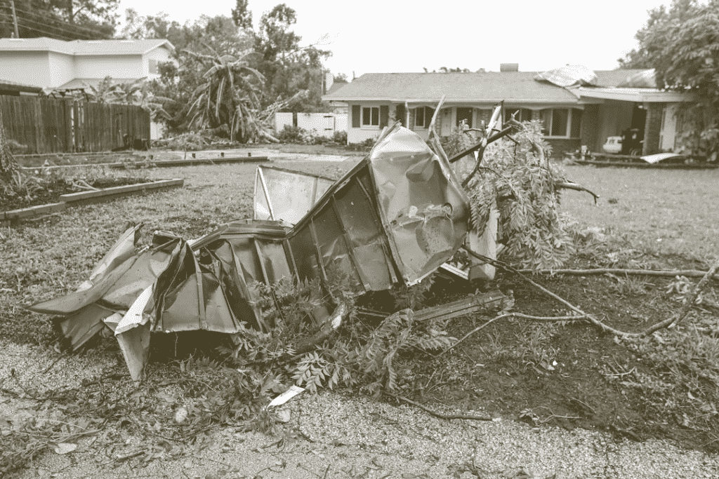 Scrap metal in front of a house that has been transported there by a hurricane