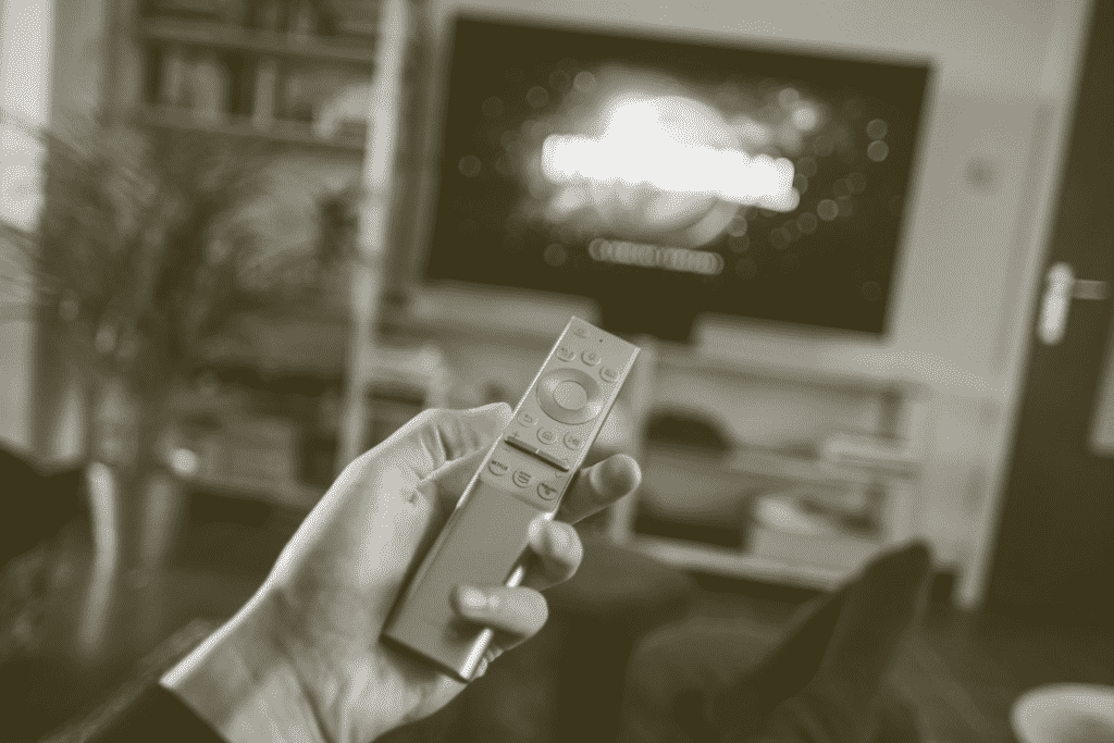 A hand holding up a TV remote
