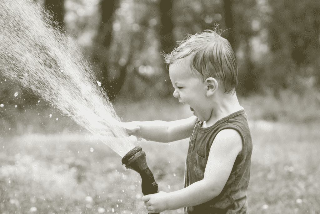 Toddler playing with hose water